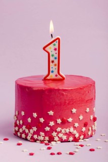 Lighted number one candle red cake with star sprinkles against purple backdrop
