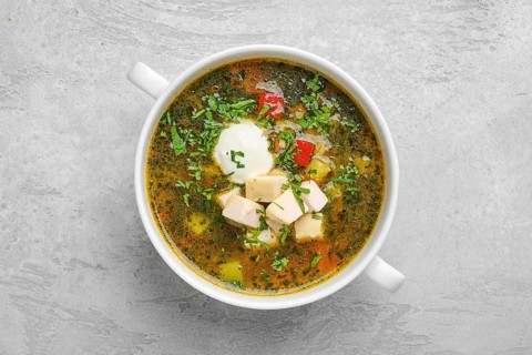 Top view of vegetable soup with chicken fillet and sour cream
