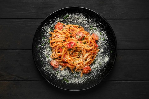Top view of spaghetti with tomato cherry and grated parmesan on a plate