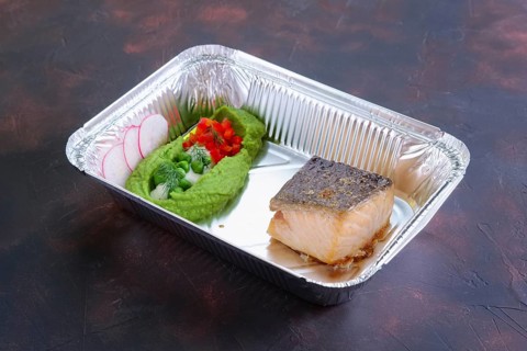 Fried salmon with pea mash decorated with radish and peas in take away packaging