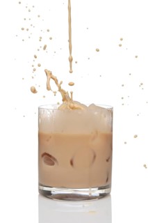 Irish creme liqueur pouring in a glass full of ice