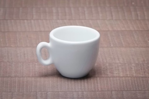 Clean and empty ceramic cup for espresso without saucer on wooden table