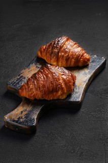 Crispy croissant on shabby wooden serving board