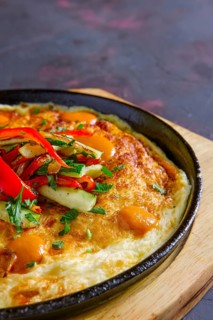 Vegetarian omelette with vegetables in cast iron pan