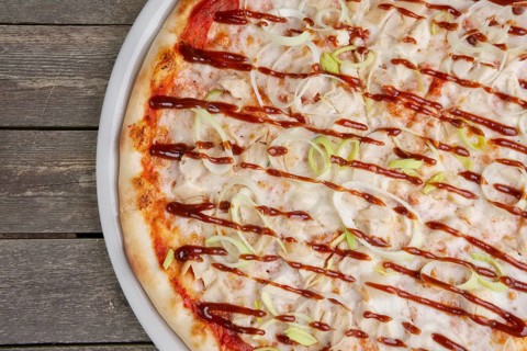 Top view of part of pizza with chicken barbecue on wooden table