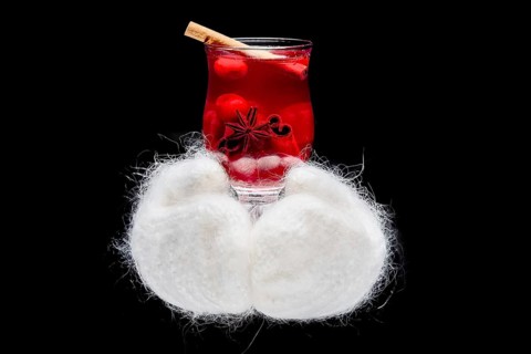 Hands in warm gloves holding hot cup with herbal tea