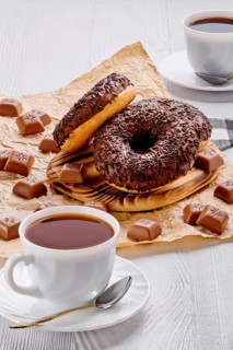 Chocolate donuts and coffee on white wooden background