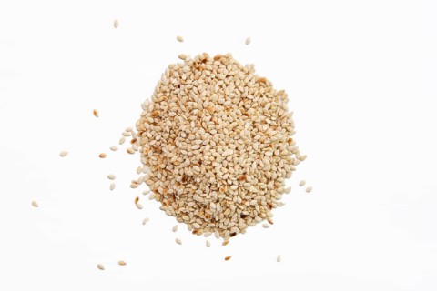 Top view of sesame seeds scattered on white paper