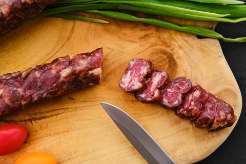 Close up view of dried pork sausage on wooden cutting board