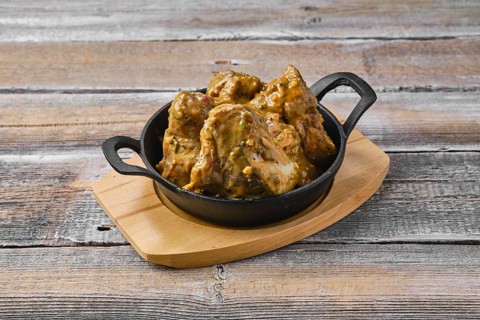 Lamb saddle marinated in mustard in cast iron skillet on wooden table