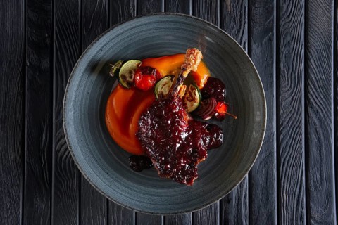Top view of fried duck thigh with carrot puree and zuccini