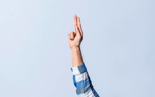 Hand gesturing the letter U in sign language on an isolated background. Man's hand gesturing the letter U of the alphabet isolated. Letter U of the alphabet in sign language