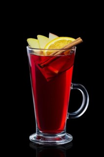 Transparent glass with hot mulled wine isolated on black