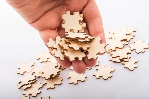 Hand holding piece of jigsaw puzzle as problem solution concept