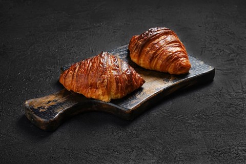 Crispy croissant on wooden serving board