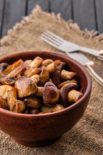 Clay plate with roasted mushrooms on dark wooden table
