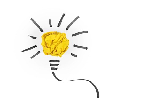 Idea concept with light bulb made out of yellow crumbled paper ball and drawn black lines on white background