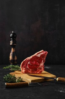 Raw strip steak bone in on dark background