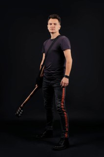 Full length portrait in low key of musician standing with guitar