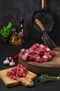 Chopping fresh beef meat for goulash or stew on wooden chopping stump