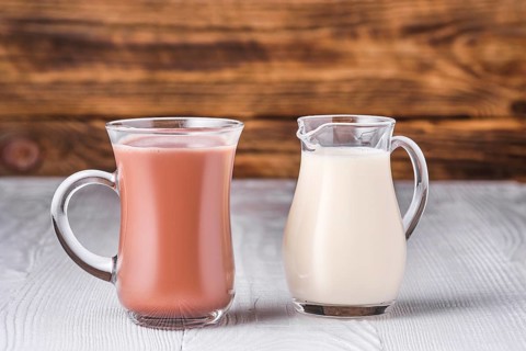 Chocolate milk and soy milk in glass on white table over dark wooden background