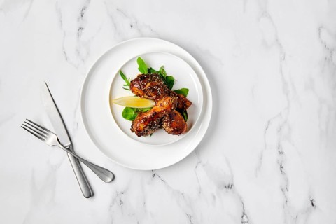 Overhead view of baked chicken legs with spicy sauce on a plate