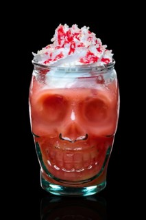 Halloween strawberry cocktail with whipped cream in skull glass isolated on black