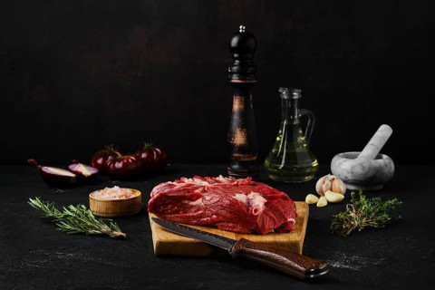 Raw beef top round roast with spices on dark background