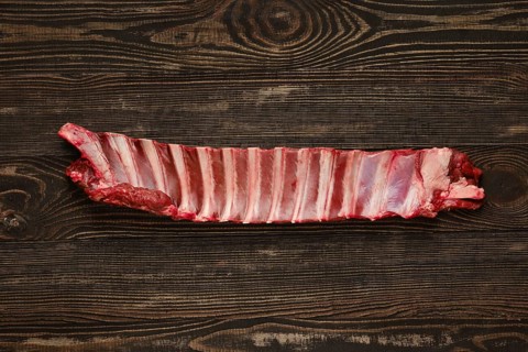Overhead view of raw deer ribs over wooden background