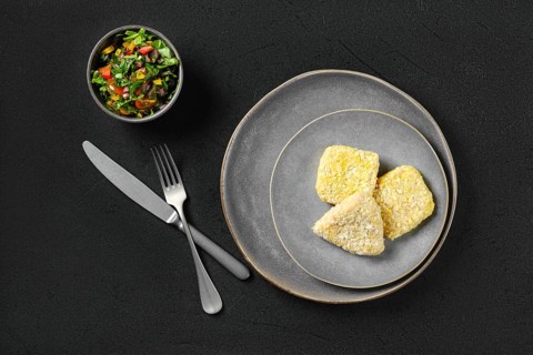 Top view of semifinished squid cutlet in breading on a plate