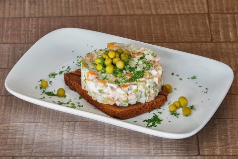 Traditional New Year's salad. Russian traditional salad olivier with pea in the plate