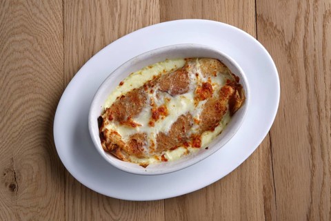 Top view of fried pancakes stuffed with ham and covered with melted cheese on wooden table