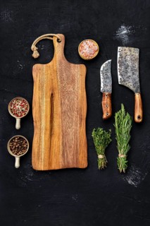 Top view of wooden cutting board with butcher tools and herbs with seasoning