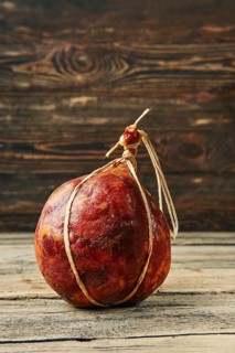 Round fermented beef sausage on wooden table
