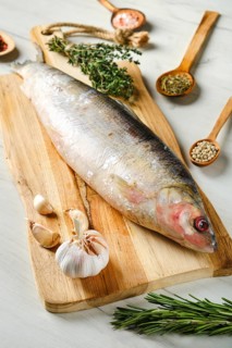 Raw frozen unpeeled omul on wooden cutting board
