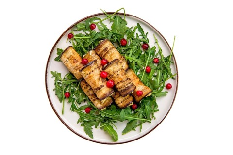 Eggplant rolls stuffed with soft cheese and garlic decorated with arugula and cranberry