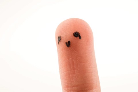 Black dots forming a face on the fingertip