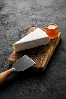 Piece of soft brie or camembert cheese on cutting board
