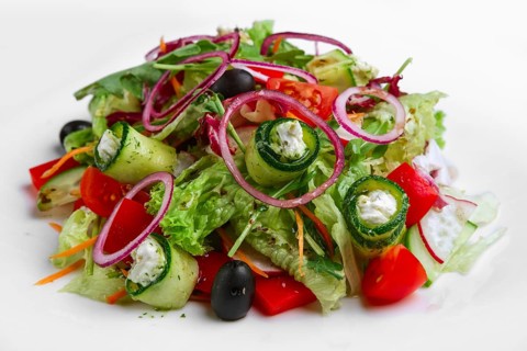 Salad with feta cheese rolled in cucumber slices with tomato and red onion