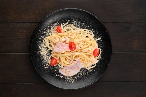 Spaghetti with ham and tomatoes sprinkled with grated parmesan
