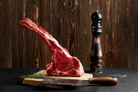 Raw prime ribeye steak on wooden cutting board