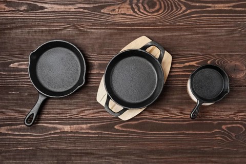 Three empty mini cast-iron skillets on wooden table