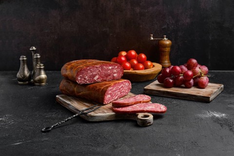 Homemade smoked beef sausage in organic casing on wooden cutting board