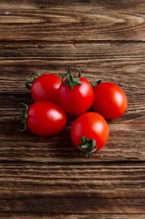 Five fresh cherry tomatoes on wooden table