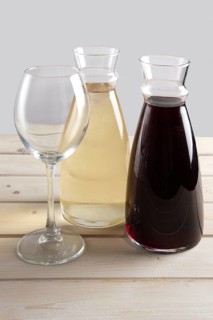Wine glass and two pitchers with red and white wine on wooden table