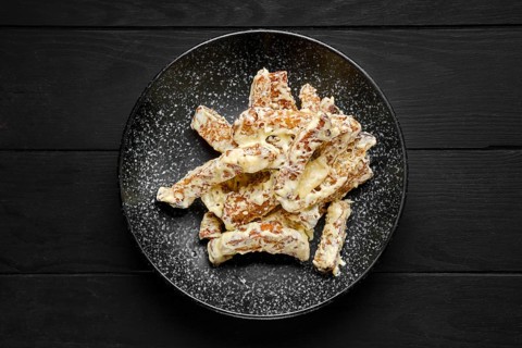 Overhead view of salty bread sticks covered with melted cheese on a plate