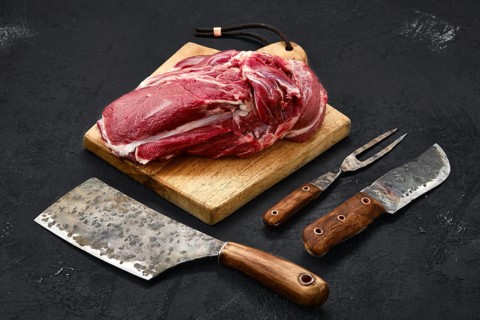 Overhead view of raw lamb shoulder without bone on wooden cutting board
