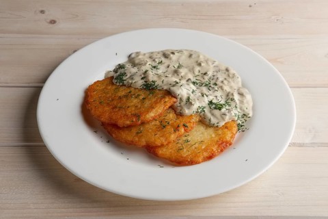 Traditional belorussian potato pancakes draniki with mushroom sauce on a plate