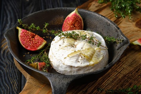 Closeup view of baked in oven camembert cheese and figs ready for baking on frying pan