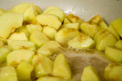 Slices of green apples caramelizing in frying pan with sugar